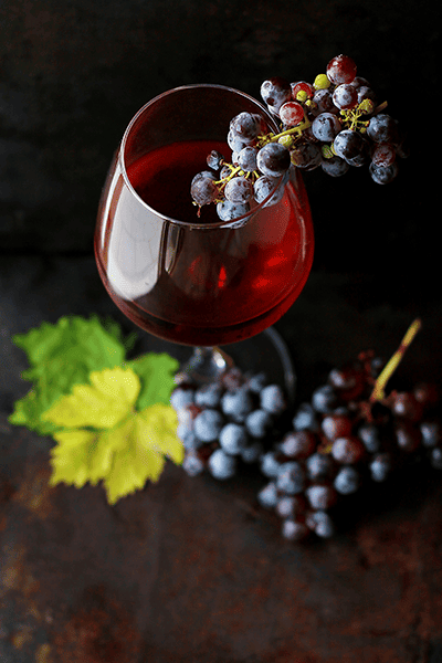 taça com vinhos e uvas roxas